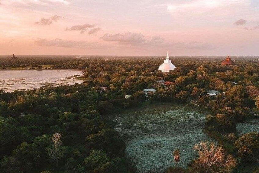 A large white temple surrounded by dense forest and a river. 3