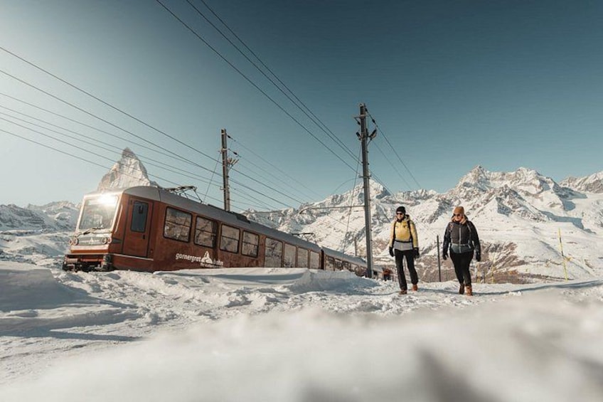 A train on a snowy mountain track with a person walking beside it. 4