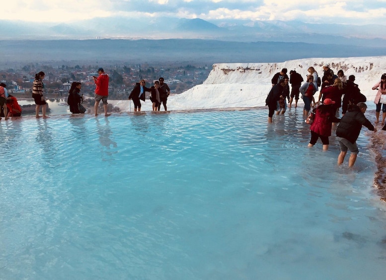A group of people standing in a natural pool with a mountainous landscape in the background. 1