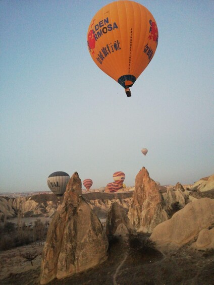 A hot air balloon with 'Golden Rmosa' written on it flying over a rocky landscape. 4