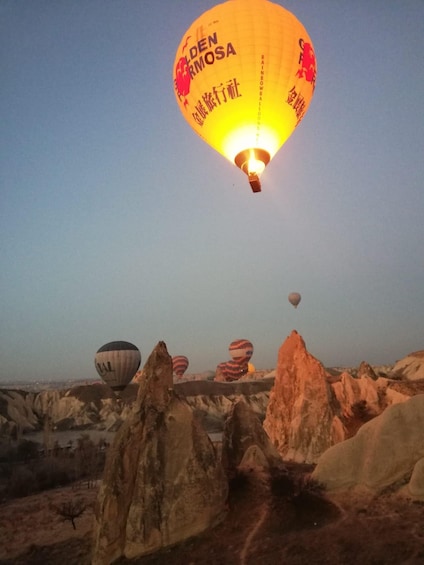 A hot air balloon with 'Golden Rmosa' written on it, flying over a rocky landscape. 5