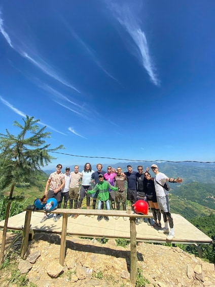 A group of people standing on a wooden platform with a scenic mountain view in the background. 3