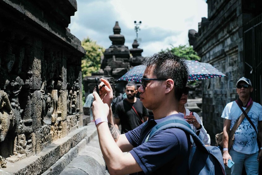 A person taking a photo of a stone structure with intricate carvings. 3