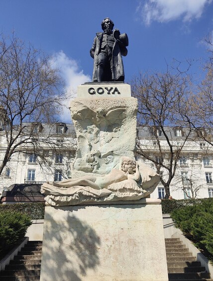 A statue of a man with a name plaque reading 'GOYA' and a relief sculpture below it. 2