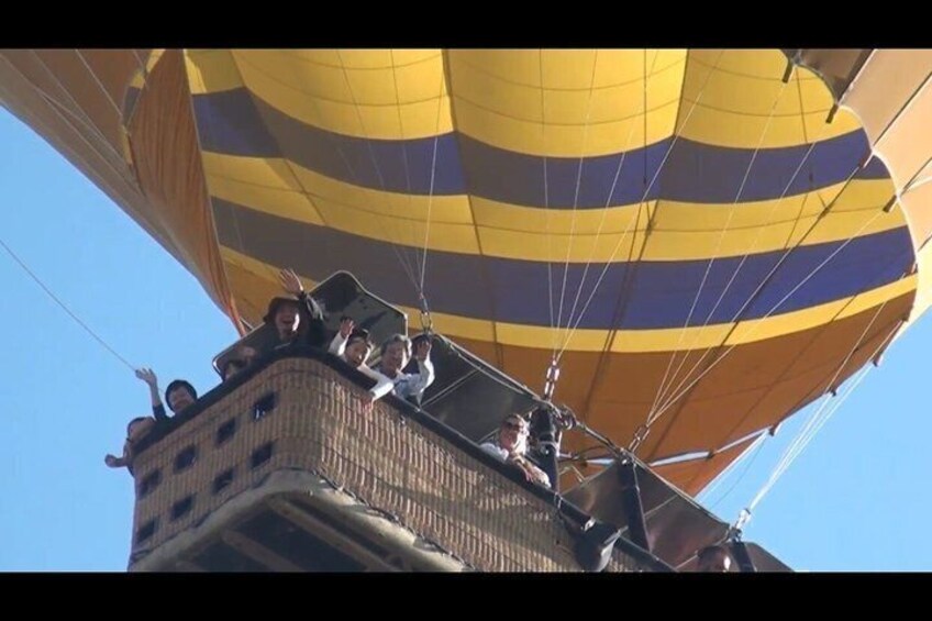A hot air balloon with passengers, a basket, and a clear sky. 5