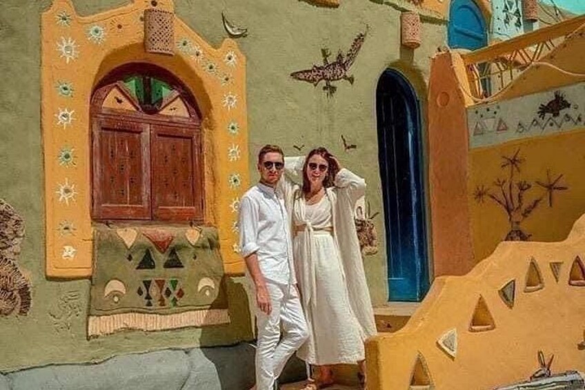 A couple standing in front of a building with colorful geometric patterns and a blue door. 5