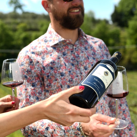 A person holding a wine bottle and pouring wine into a glass. 1