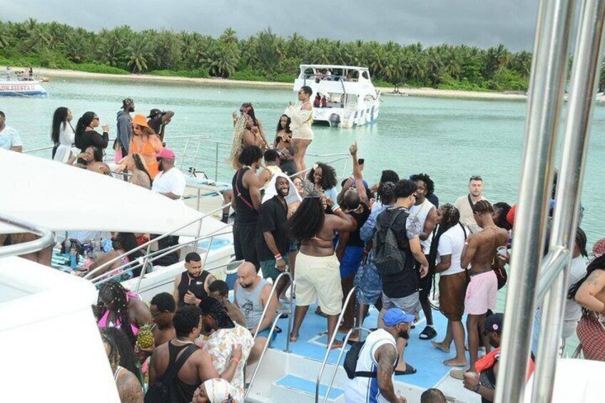 A group of people on a boat near a shoreline with a small boat in the background. 3