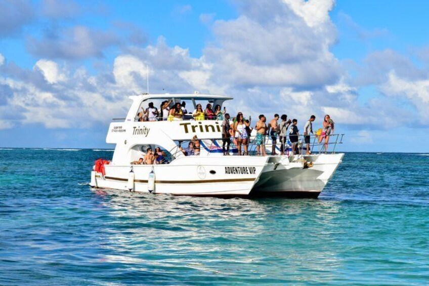A white boat named 'Trinity' with 'Adventure VIP' written on the side, floating on calm blue waters. 1