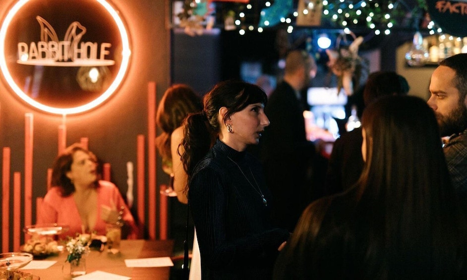 A bar with a neon sign reading 'DABBIT HOLE' and people standing around. 5