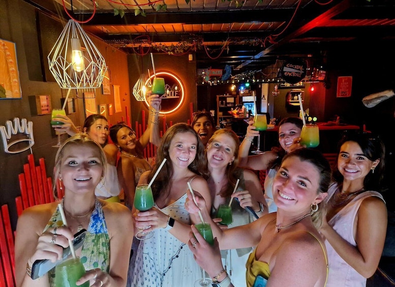 A group of people in a dimly lit bar with neon signs and red accents. 1