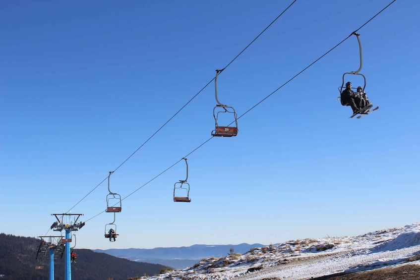A ski lift with chairs suspended on cables against a clear blue sky. 2