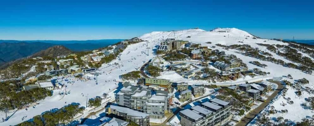 A snow-covered mountain town with buildings, roads, and a ski slope. 5