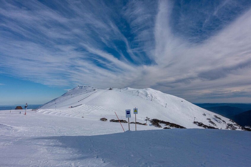 A snow-covered mountain with ski trails, a ski lift, and a clear sky with wispy clouds. 3