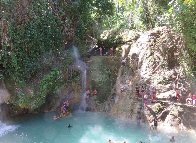 A natural hot spring surrounded by lush greenery and rocky terrain. 2