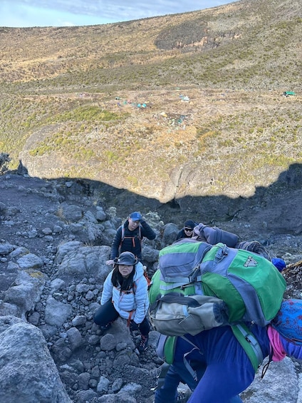 A group of hikers navigating a rocky terrain with a mountainous backdrop. 2