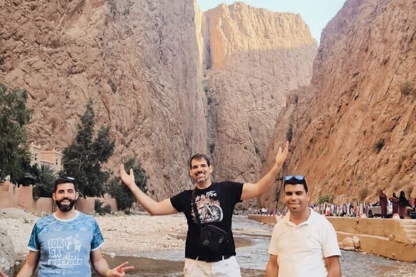 Three people standing in a canyon with steep rock walls and a river. 2