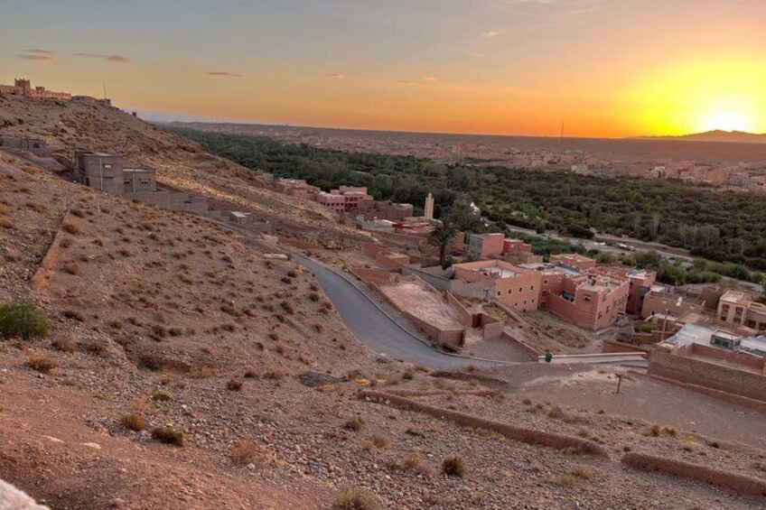 A desert landscape with a winding road, traditional buildings, and a distant hill with a structure. 3