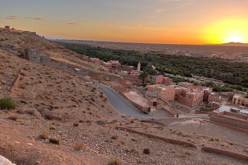 A desert landscape with a winding road, buildings, and a distant hill with a structure on top. 3