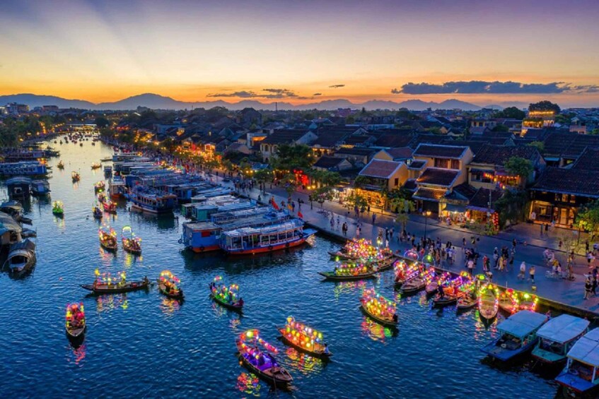 A riverside town at dusk with boats decorated with lights. 1
