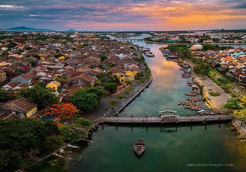 An aerial view of a riverside town with boats docked along the riverbanks and a bridge connecting two parts of the town. 2