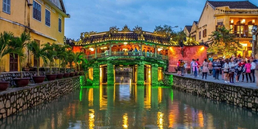 A traditional Vietnamese bridge with green lighting, surrounded by stone walls and potted plants. 5