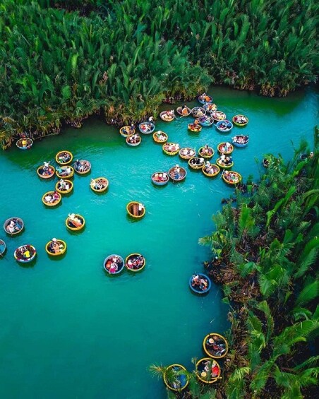 A river with numerous small boats filled with people, surrounded by dense green foliage. 4