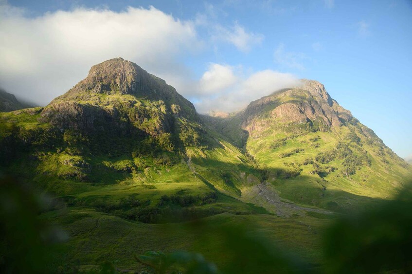 A mountainous landscape with lush green hills and a prominent peak. 1
