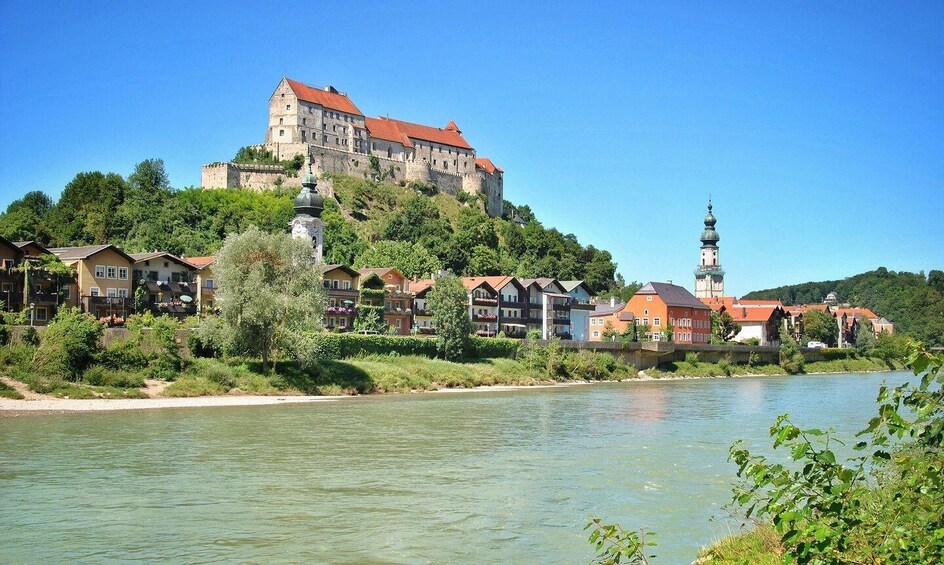 A riverside town with a castle on a hill, a church with a tall spire, and residential buildings along the water. 5