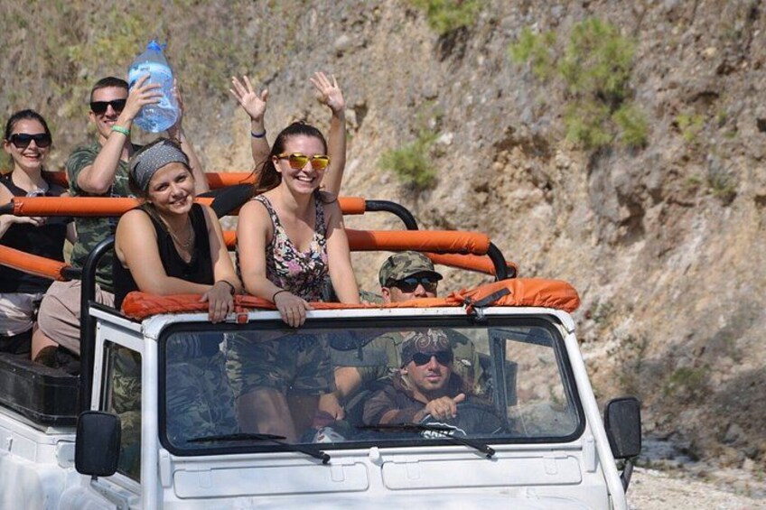 A white vehicle with orange railings and passengers waving. 1
