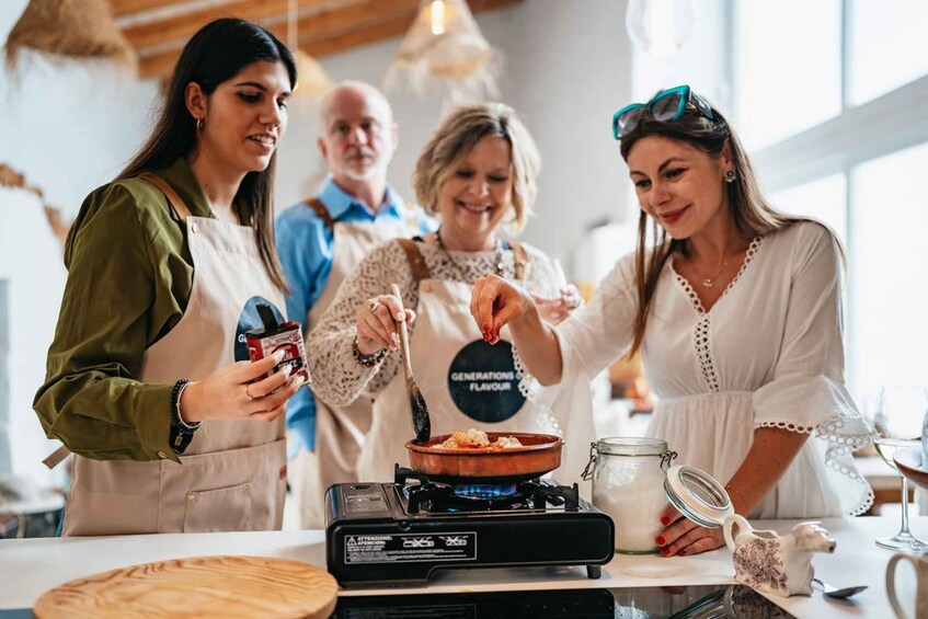 Three people cooking with a portable stove, a jar, and a teapot on a table. 5