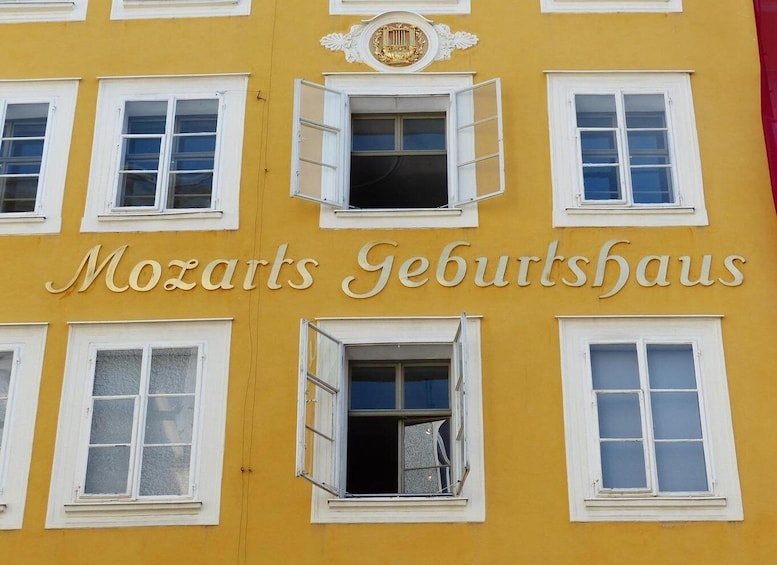 A yellow building with the sign 'Mozarts Geburtshaus' and white-framed windows. 4