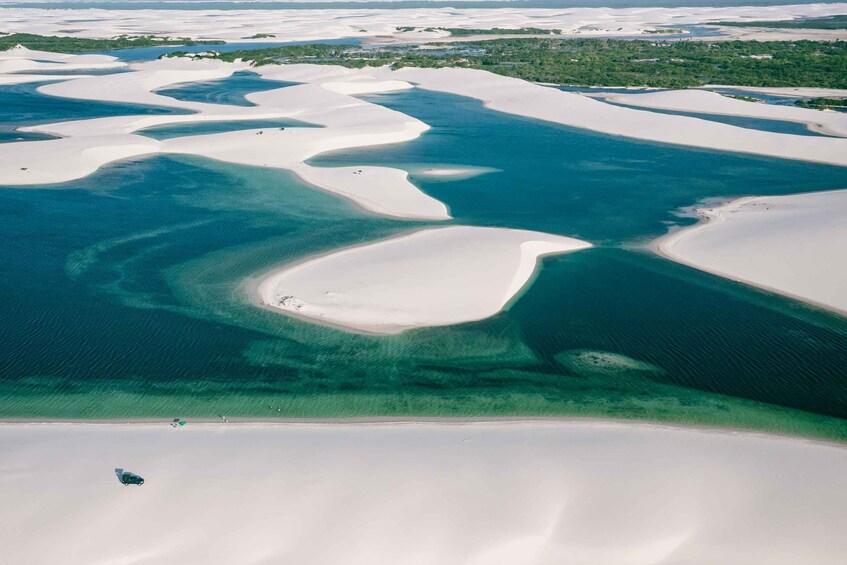 An aerial view of a coastal area with white sand dunes and clear blue waters. 3