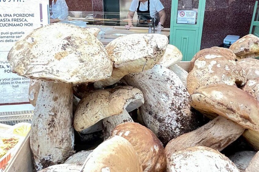 Un montón de hongos grandes, probablemente porcini, en un mercado. 3