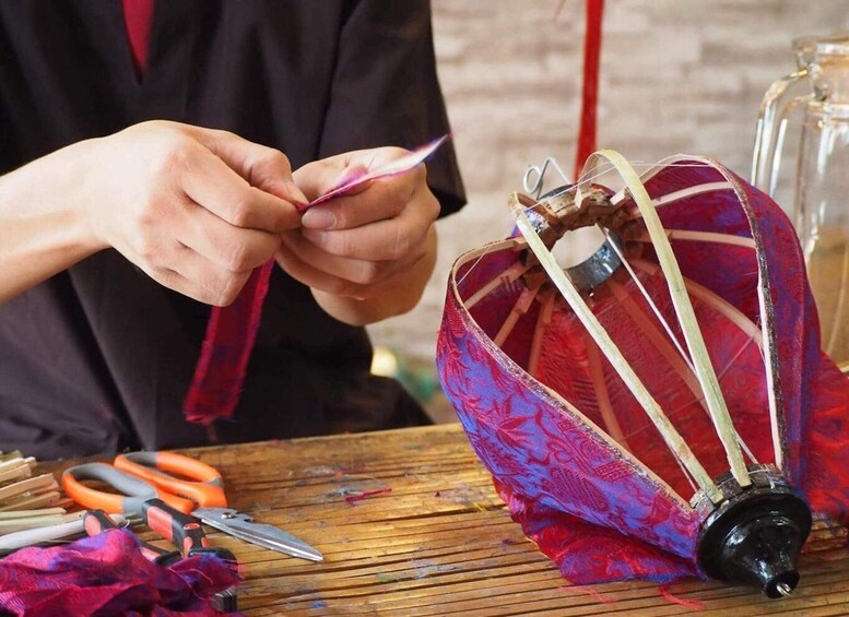 A person working on a colorful, patterned fabric with tools on a wooden surface. 1