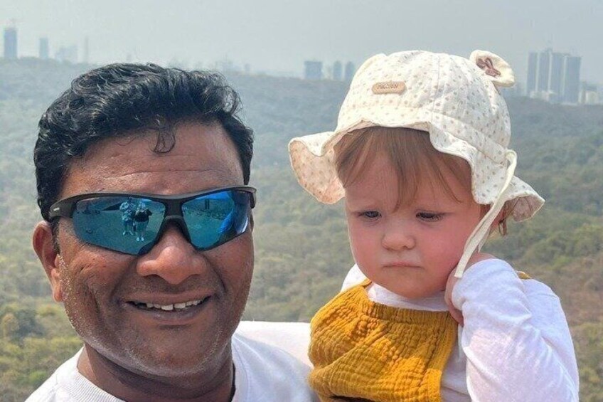 A person holding a child with a city skyline in the background. 2
