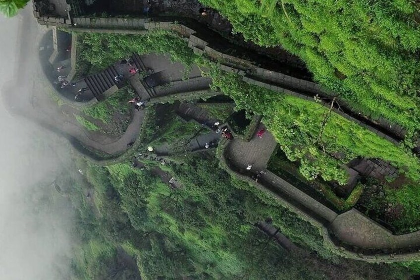 A lush green landscape with a winding path and stone structures. 1