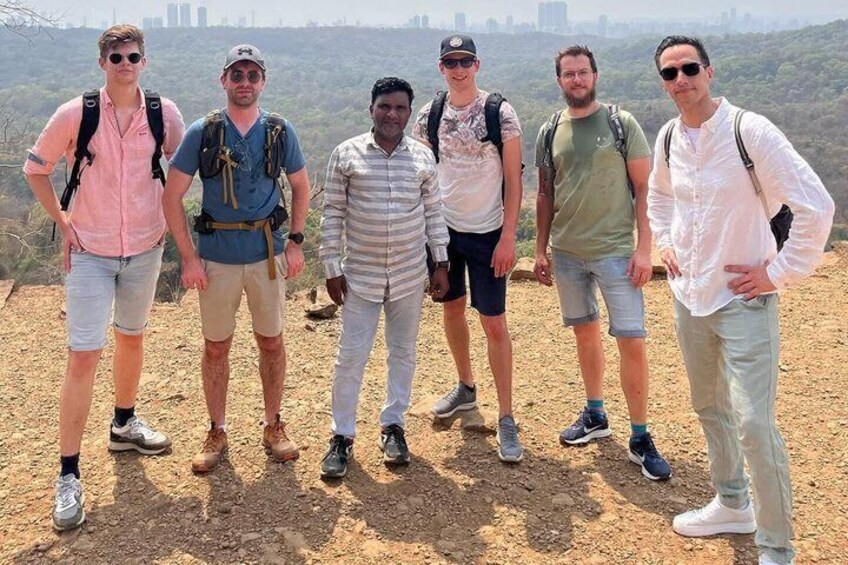 A group of people standing on a dirt path with a hilly landscape in the background. 3