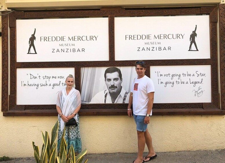 Reklameskilt med to paneler for Freddie Mercury Museet i Zanzibar, der viser citater og en silhuet af Mercury. 2