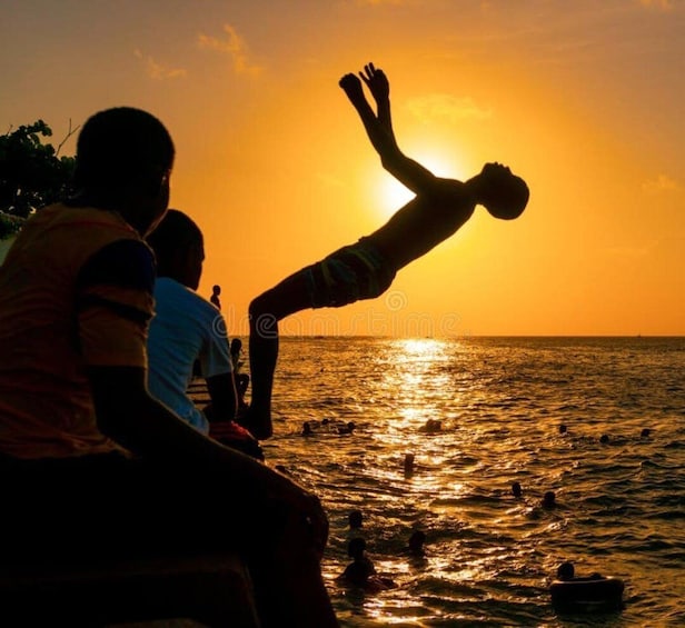 Tramonto su un corpo d'acqua con persone sedute e che nuotano. 2