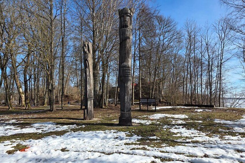 Un parc où le sol est recouvert de neige, les arbres sont sans feuilles et on y trouve une sculpture en bois. 5