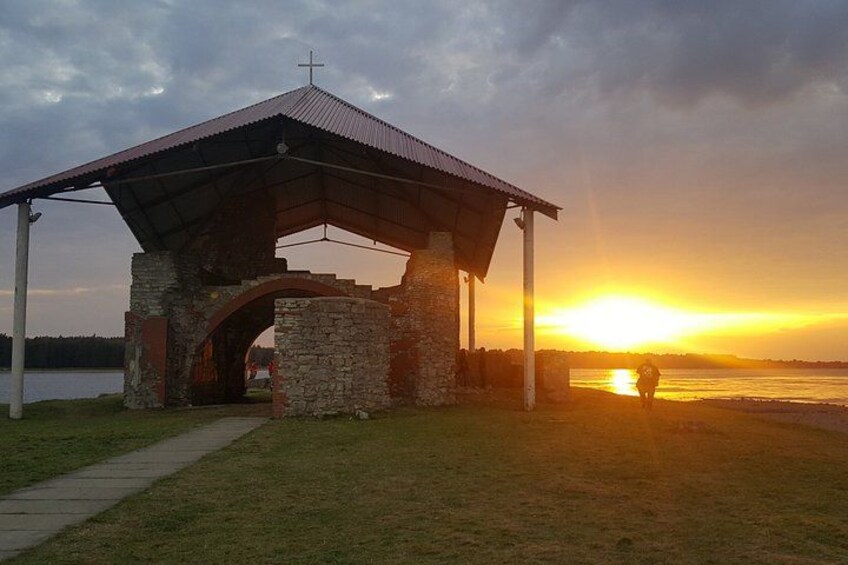 Une structure en pierre surmontée d’une toiture métallique et d’une croix, et une personne s’éloignant de celle-ci. 1