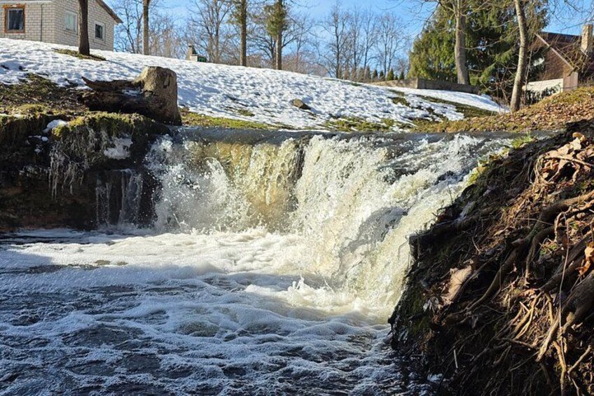 Une cascade d’eau se déversant sur des rochers, entourée d’un paysage enneigé et d’arbres. 4