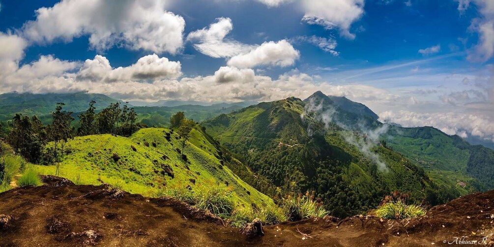 A mountainous landscape with lush green hills and a prominent peak emitting smoke. 2