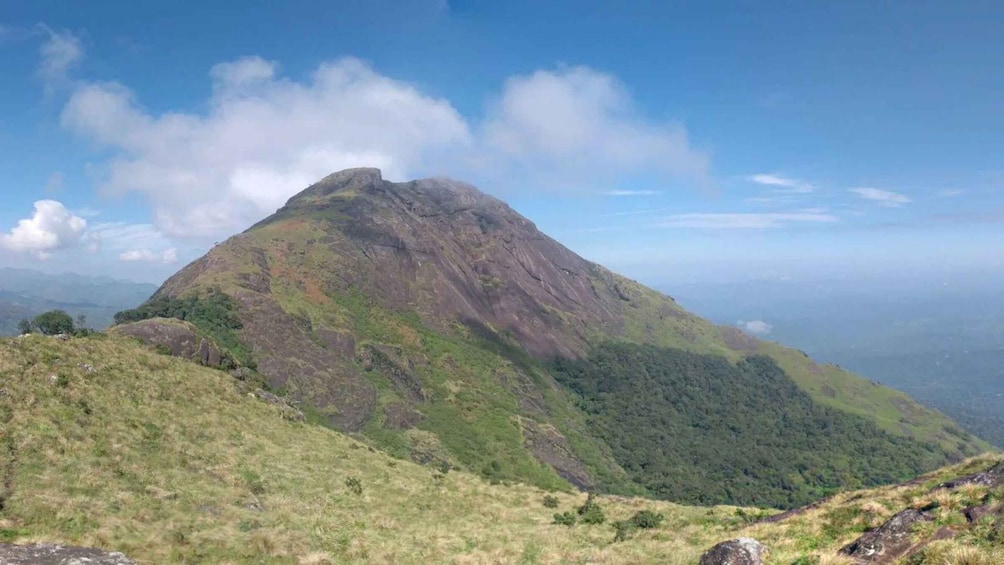 A mountain with a peak, surrounded by green vegetation and a clear sky. 4