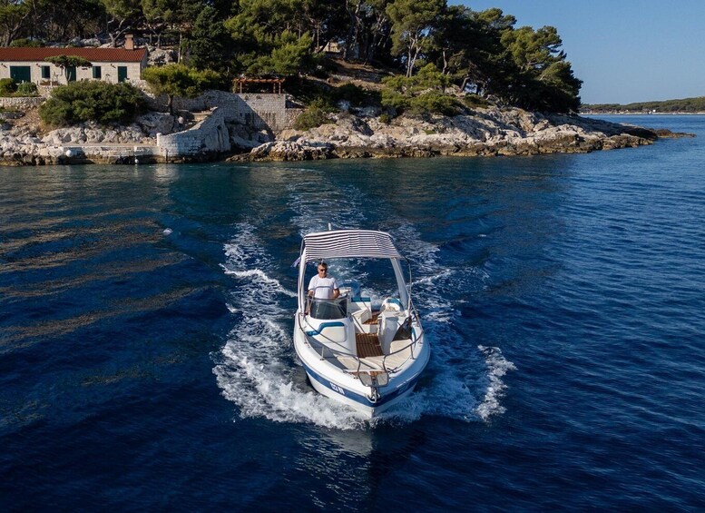 A boat moving on a calm sea with a rocky shore and trees in the background. 1