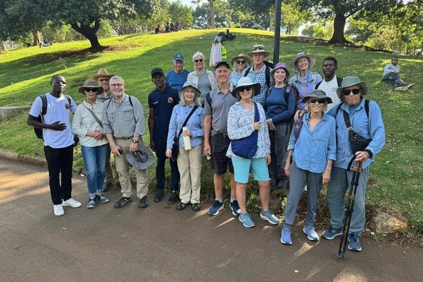 Un gruppo di persone su un vialetto lastricato in un parco, con erba e alberi sullo sfondo. 2