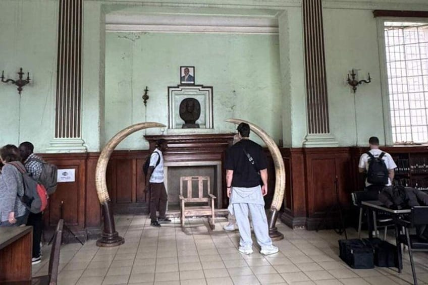 Un'aula di tribunale con la cattedra del giudice, una grande struttura in legno curvata, e persone in piedi. 4