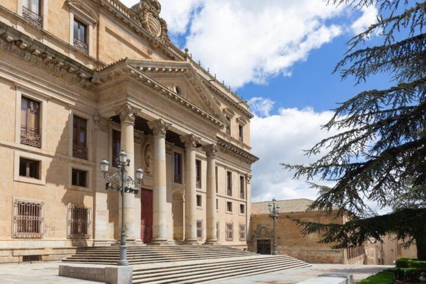 A classical building with columns, a red door, and a staircase leading to the entrance. 2