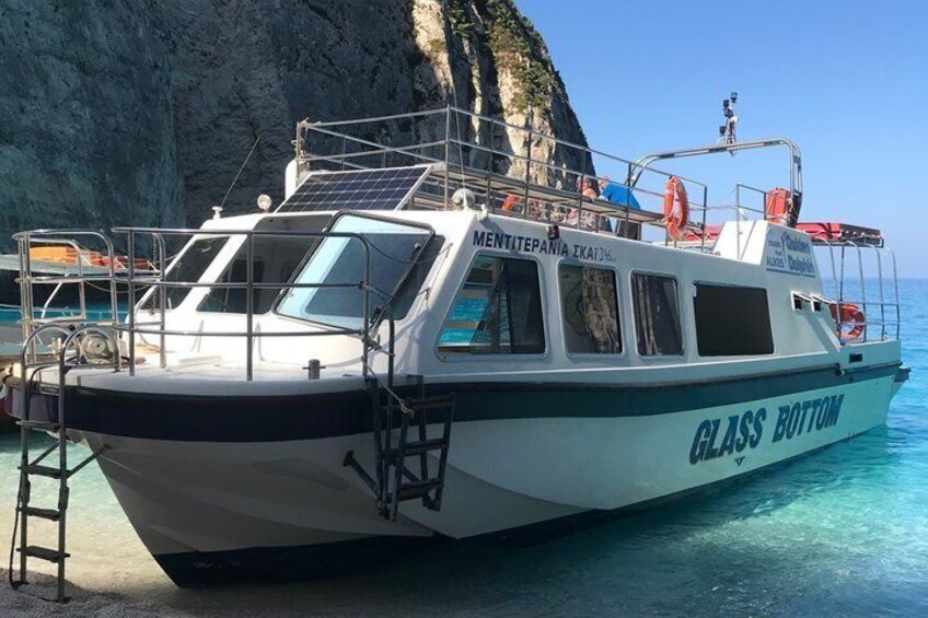 Un barco llamado 'GLASS BOTTOM' amarrado en una zona costera rocosa. 1